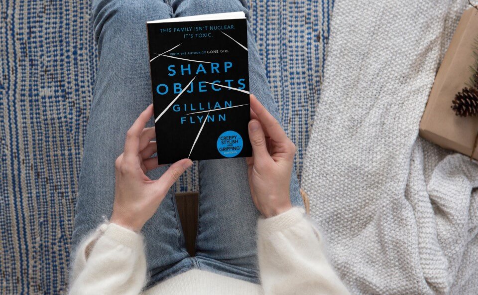 Woman holds Sharp Objects book in her hands