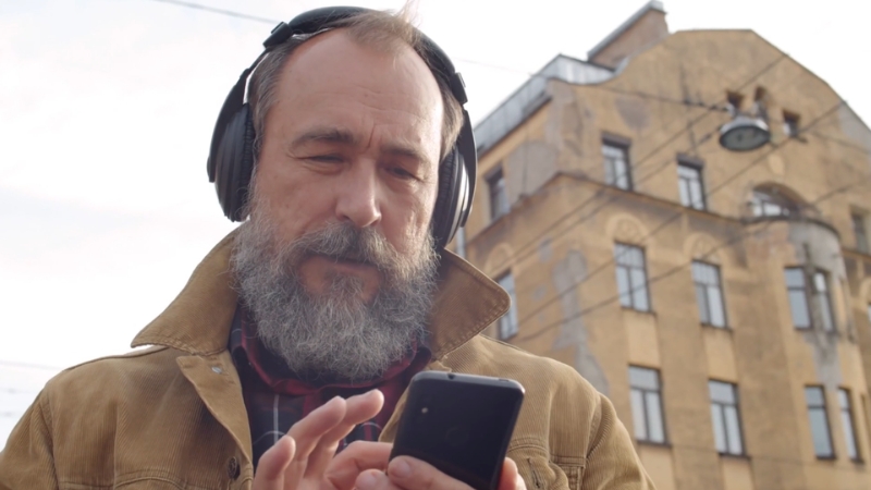 Man with headphones outdoors using a smartphone to listen to audiobooks while walking