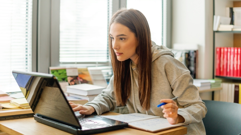 Woman studying at a desk with a laptop and notebook, illustrating practical tips and best practices for reading tracking