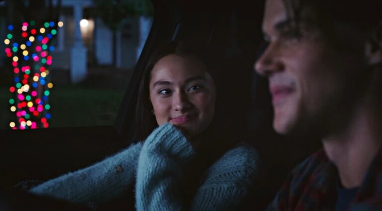 A close-up of Belly, smiling softly, as she sits in a car