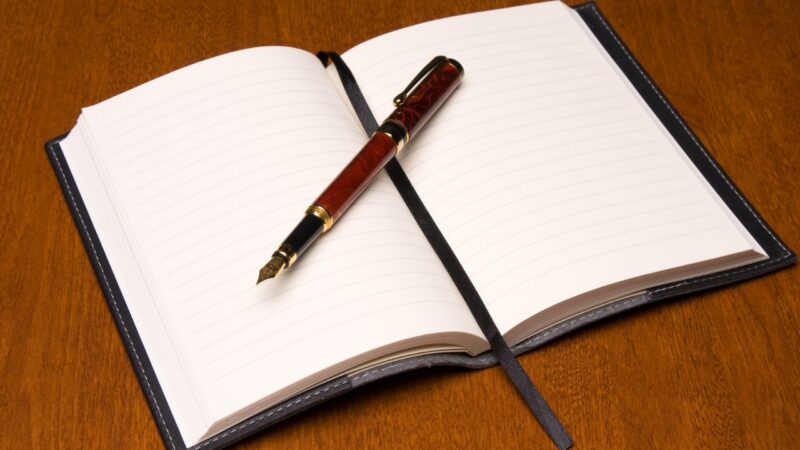Open reading journal with a fountain pen on a wooden desk