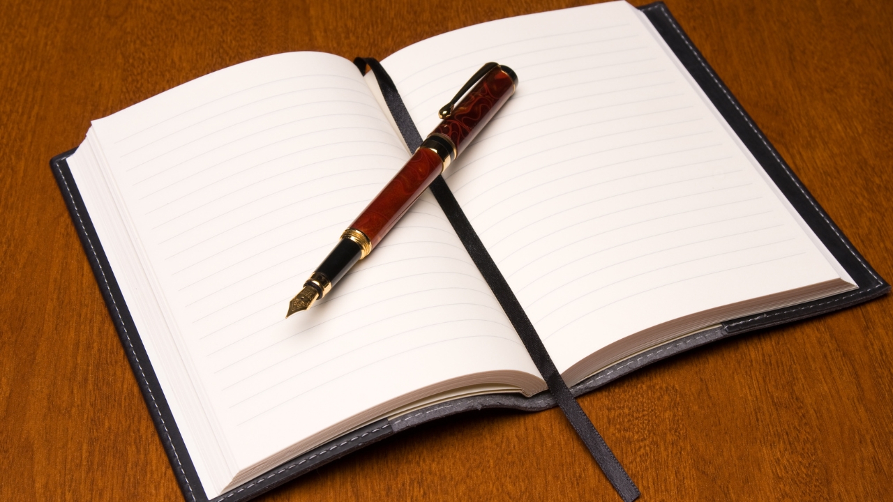 Open reading journal with a fountain pen on a wooden desk